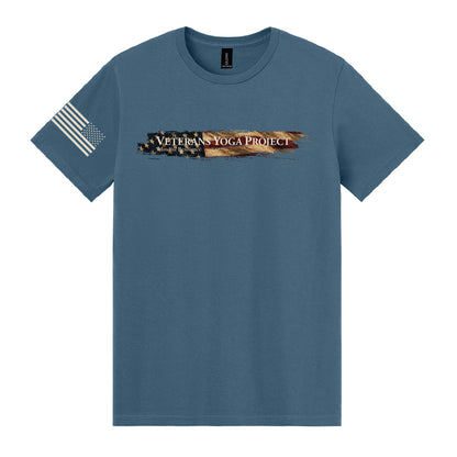An indigo tee with the Veterans Yoga Project logo across the chest, backed by a vintage American flag graphic.